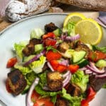 Low carb Brotsalat mit Croutons aus altem Eiweißbrot, Tomaten, roten Zwiebeln, Paprika und Gurken auf einem Teller