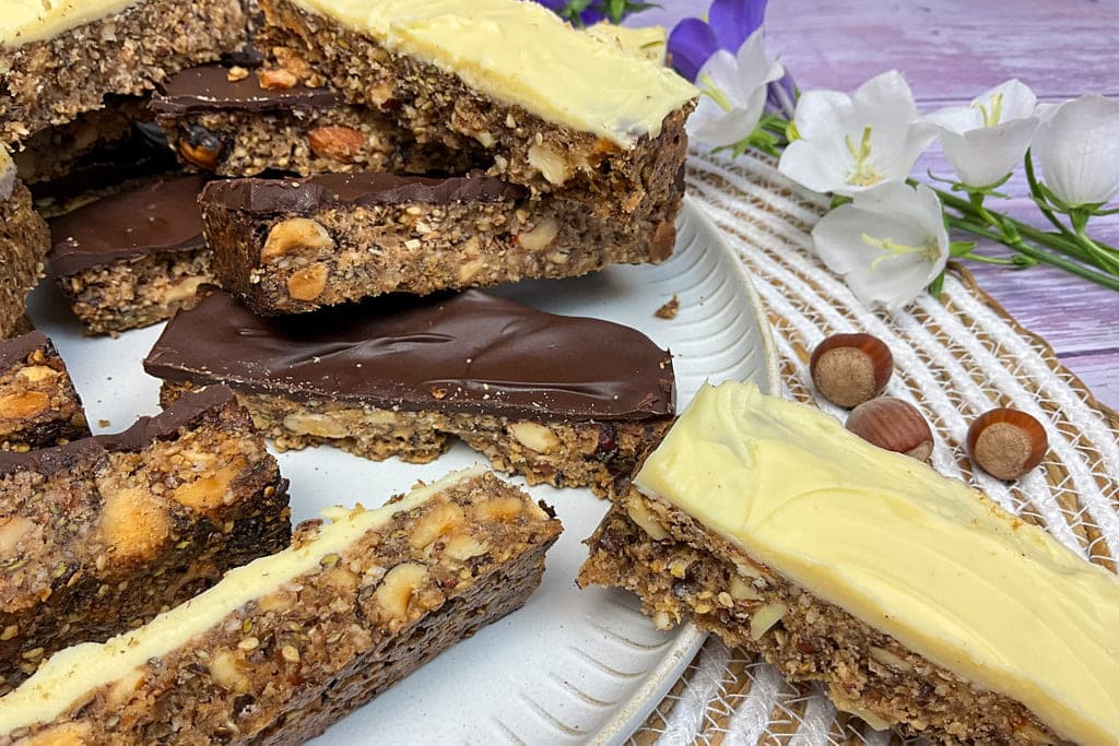 Low carb Müsliriegel mit zartbitter und weißer Schokolade und Haselnüssen auf einem Teller