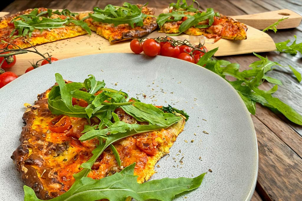 Fertig gebackener High Protein Pizzateig belegt mit Salami, Tomaten, Käse und Rucola