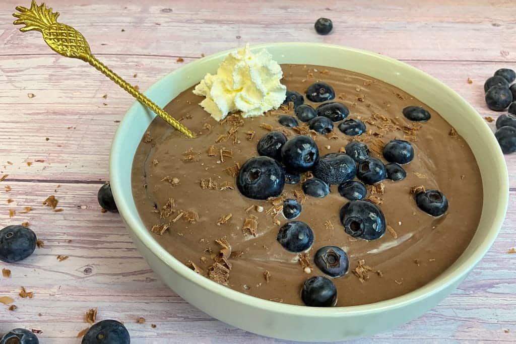 Schokoladen Protein Pudding vegan und zuckerfrei in einer Schale mit Heidelbeeren und Schokoraspeln