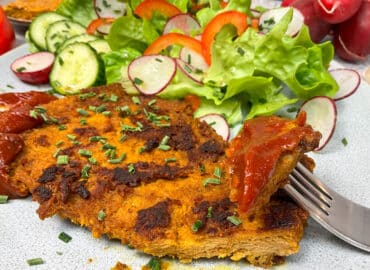 Veganes Steak Rezept mit leckerer Marinade: Angeschnittenes veganes Steak mit Barbecue Sauce und Salat auf einem Teller